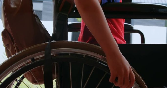 Side view of disabled African American schoolboy moving his wheelchair in school corridor 4k