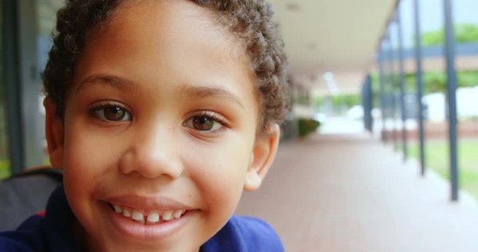 Close-up of happy disabled African American schoolboy sitting on wheelchair in school corridor 4k
