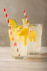 two glasses of lemonade with lemons and lime and straw, a cool drink and summer mood, with ice