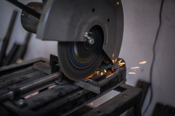Naklejka na ściany i meble Cutting metal with grinder in workshop. Sparks while grinding iron. Cutting machine