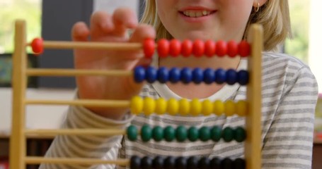 Front view of Caucasian schoolgirl learning mathematics with abacus in the classroom 4k - Powered by Adobe
