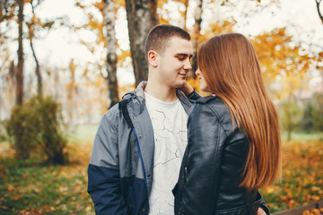 Fototapeta premium Cute couple walking in a autumn park. Boy in a black jacket. Girl in a gray dress