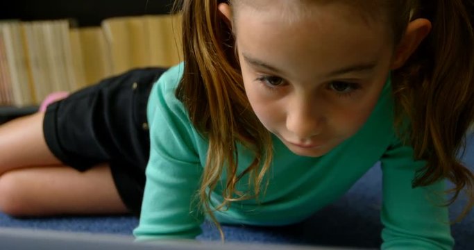 Front view of attentive Caucasian schoolgirl studying with laptop in library at school 4k - Powered by Adobe