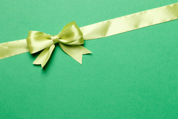 Light green ribbon and bow on a green background. The concept of gifts.