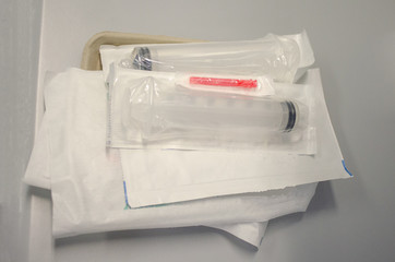 Packaged, sterile needle, syringe and dressings on a tray in a hospital.