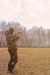 The hunter aims at the sky with a gun. Spring Forest. Duck Hunt.