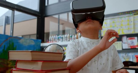 Front view of Asian schoolboy using virtual reality headset in classroom at school 4k - Powered by Adobe
