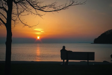 Blur background, no focusing -Abstract image for the background. A man sitting on a bench by the sea at sunset.