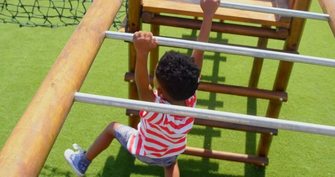 High angle view of African American schoolboy playing on horizontal ladder in school playground 4k