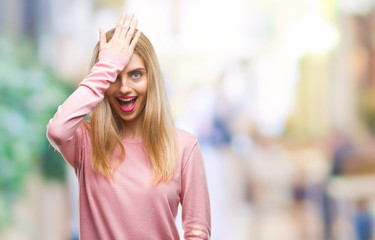 Young beautiful blonde woman wearing pink winter sweater over isolated background surprised with...