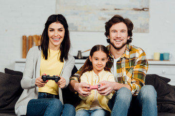 handsome man sitting near happy kid and playing video game at home