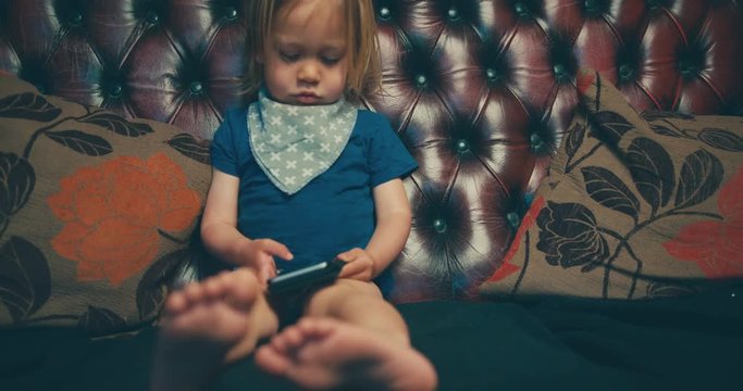 Little toddler using smartphone on sofa