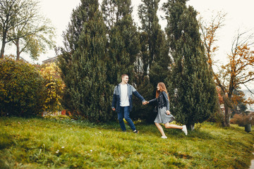 Naklejka na ściany i meble Cute couple walking in a autumn park. Boy and girl have fun