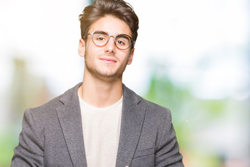 Young business man wearing glasses over isolated background Hands together and fingers crossed smiling relaxed and cheerful. Success and optimistic