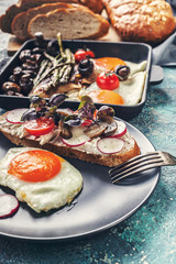 Fried eggs, sandwich with cheese, mushrooms, radishes and greens. Breakfast. Vertical shot