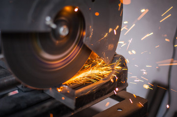 Fototapeta na wymiar Cutting metal with grinder in workshop. Sparks while grinding iron. Cutting machine