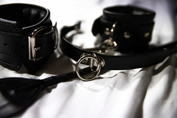Leather handcuffs, leather whip,leather open mouth gag on white background. BDSM Kit