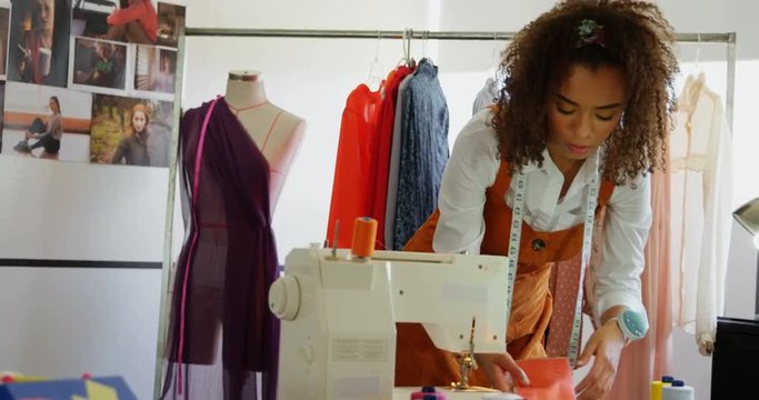 Front view of African American female fashion designer looking at cloth samples in workshop 4k
