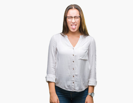 Young caucasian beautiful business woman wearing glasses over isolated background sticking tongue out happy with funny expression. Emotion concept.