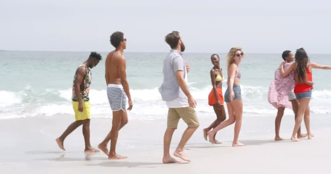 Side view of mixed-race friends walking on the beach 4k