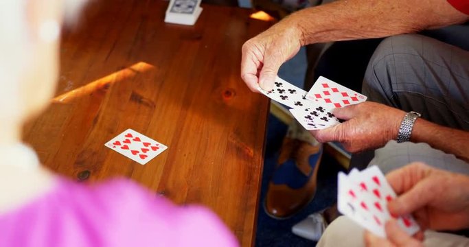 Mid section of senior people playing cards at nursing home
