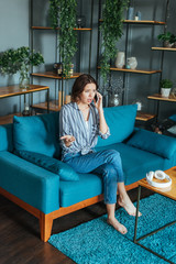 Obraz premium upset woman gesturing while talking on smartphone in living room