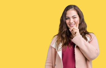 Beautiful plus size young woman wearing winter coat over isolated background looking confident at the camera with smile with crossed arms and hand raised on chin. Thinking positive.