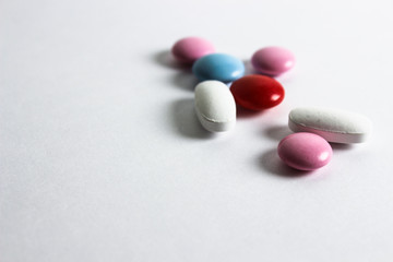 Pills on white background. Medical care and treatment. Medicine and pills, medications on white background. Colorful pink, red, white and blue  drugs.