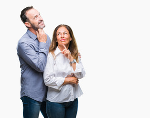 Middle age hispanic business couple over isolated background with hand on chin thinking about question, pensive expression. Smiling with thoughtful face. Doubt concept.