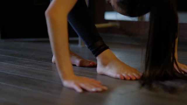 barefoot girl shows pose bends body to floor leans on hands