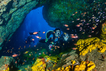 SCUBA diver swimming through an underwater cave in the Mergui Archipelago, Myanmar