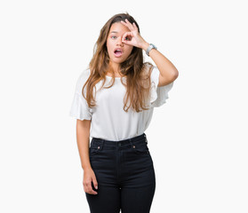 Fototapeta premium Young beautiful brunette business woman over isolated background doing ok gesture shocked with surprised face, eye looking through fingers. Unbelieving expression.