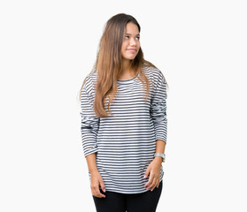Young beautiful brunette woman wearing stripes sweater over isolated background looking away to side with smile on face, natural expression. Laughing confident.