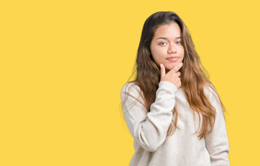 Young beautiful brunette woman wearing turtleneck sweater over isolated background looking confident at the camera with smile with crossed arms and hand raised on chin. Thinking positive.