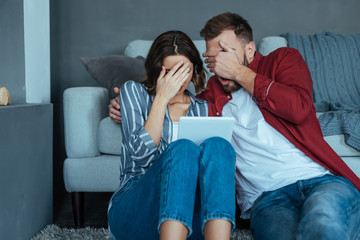 Naklejka premium woman and man covering faces while watching video on digital tablet
