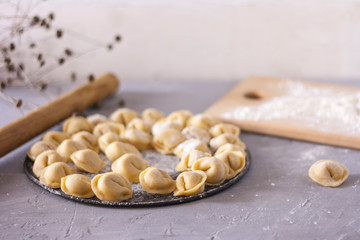 Homemade ravioli on a round platter on the table with flour and rolling pin