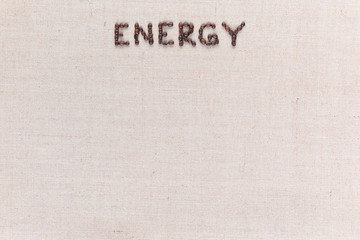 Energy word made from coffee beans on linen texture aligned top center.