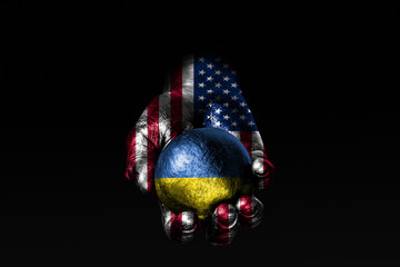 A hand with a drawn USA flag holds a ball with a drawn Ukraine flag, a sign of influence, pressure...
