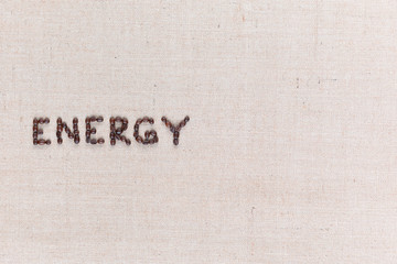 Energy word made from coffee beans on linen texture aligned middle left.