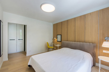 Fototapeta na wymiar Simple bedroom interior with double bed, nightstand, small glass table , white bedding and wardrobe