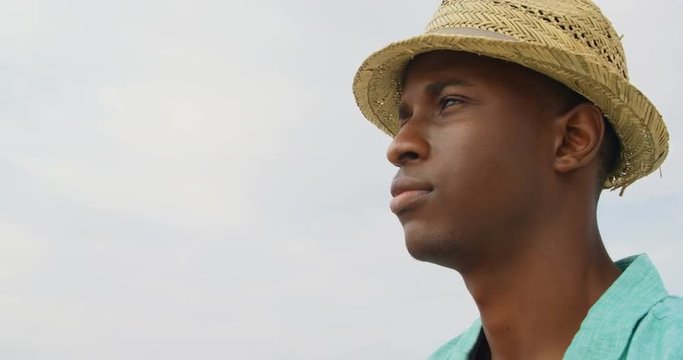 Side view of African American man in hat standing on the beach 4k
