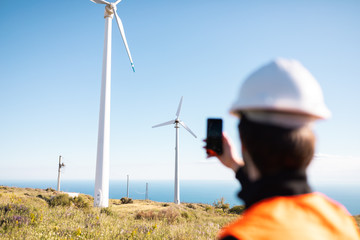Ingegnere sta fotografando l'impianto eolico, composto da una turbina movimentata dal vento. Concetto di fonte rinnovabile e manutenzione.