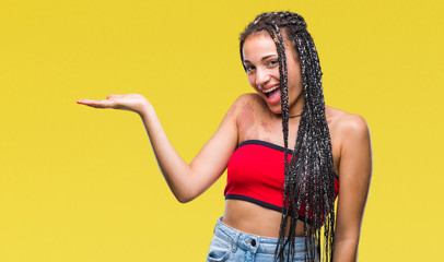 Young braided hair african american with pigmentation blemish birth mark over isolated background smiling cheerful presenting and pointing with palm of hand looking at the camera.