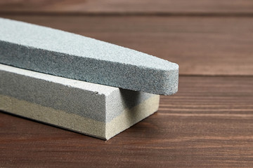 Two grindstones. Oval and rectangular double layer sharpening stone. Whetstone sharpener on wooden table background