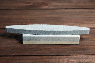 Two grindstones. Oval and rectangular double layer sharpening stone. Whetstone sharpener on wooden table background