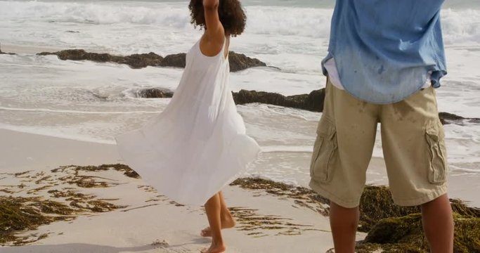 Rear view of African american man taking photos of woman with mobile phone on the beach 4k