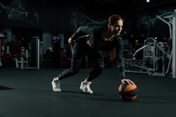 Slim woman in sportswear training with a ball