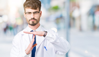Young professional scientist man wearing white coat over isolated background Doing time out gesture with hands, frustrated and serious face
