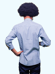 Young african american business man with afro hair wearing glasses standing backwards looking away with arms on body