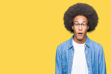 Obraz na płótnie Canvas Young african american man with afro hair wearing glasses afraid and shocked with surprise expression, fear and excited face.